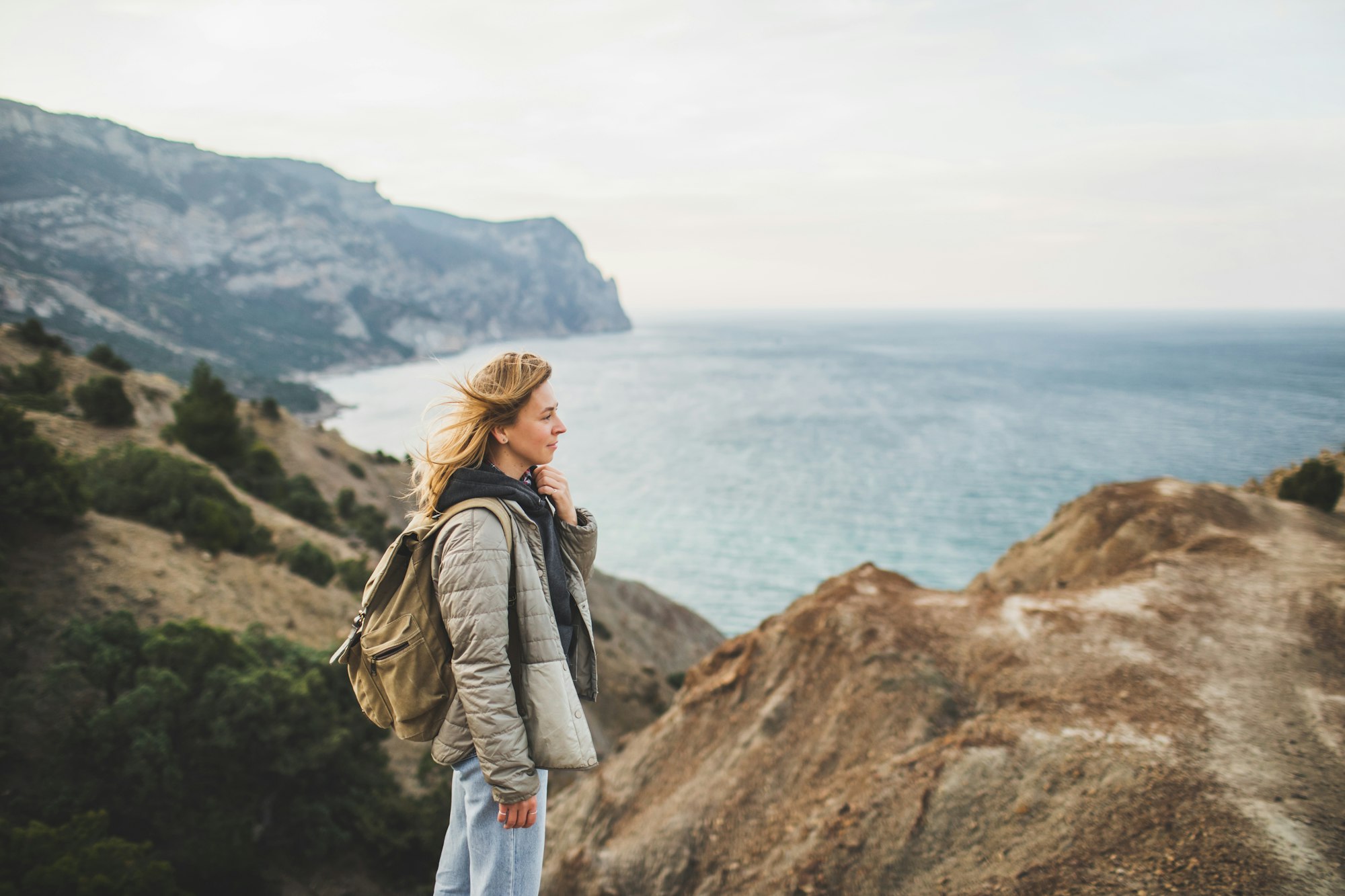 Happy young traveler woman walking and enjoying amazing coastline mountain view.