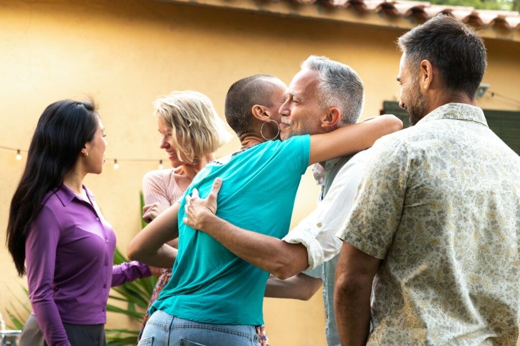 Friends arriving to garden dinner party. Hosts welcoming guests.