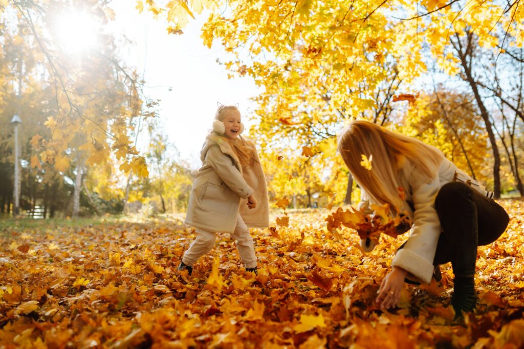 Portrait of happy mother and daughter in autumn forest at sunset. Autumn women.